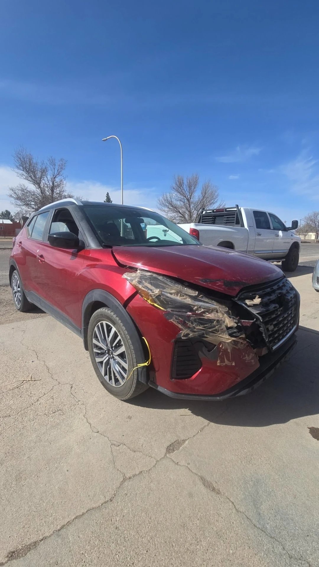 Red Nissan Kicks with heavy front-end collision damage before repair